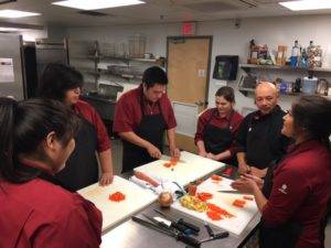 Students learning about knife skills with Chef Li in the kitchen