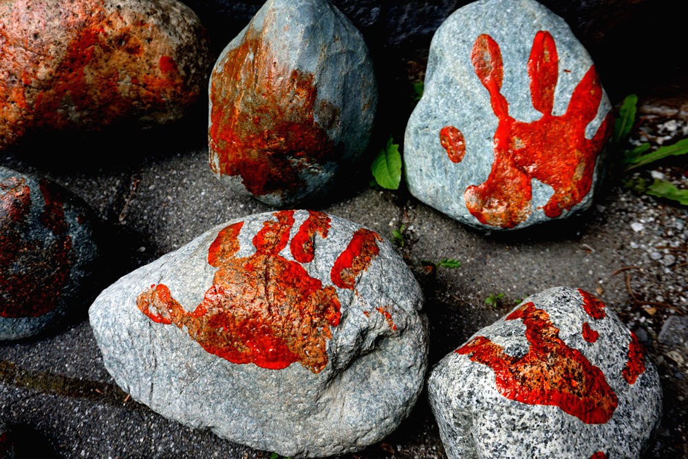 Rocks painted with orange hands, placed outside of the SLCC's front doors