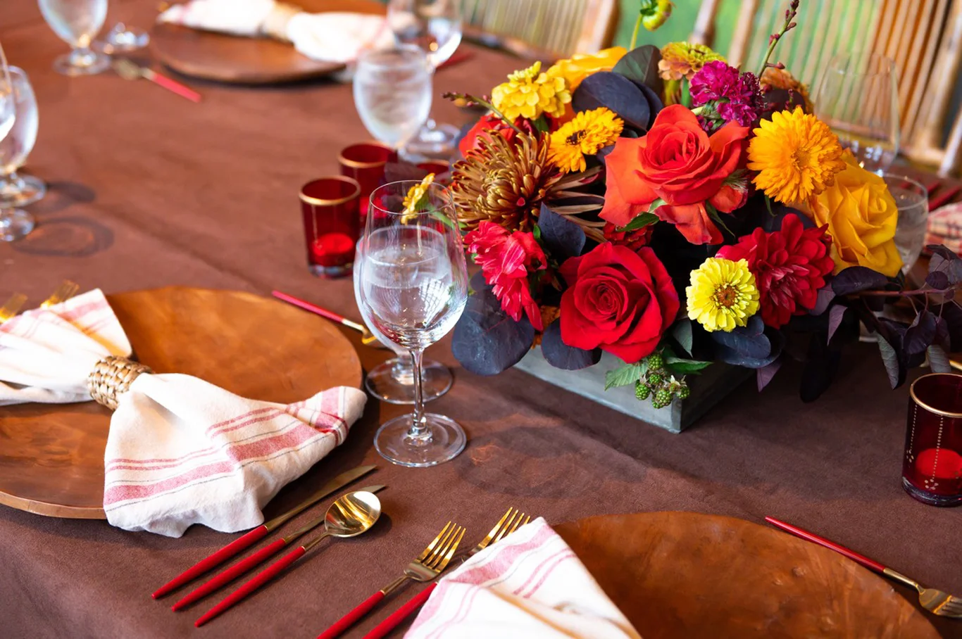 Close-up of table setting with red, orange and yellow floral centerpiece