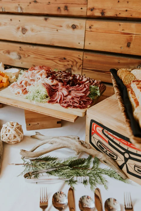Close-up of a wedding charcuterie board with cured meats and traditional Indigenous design on a wooden box at a Whistler venue.