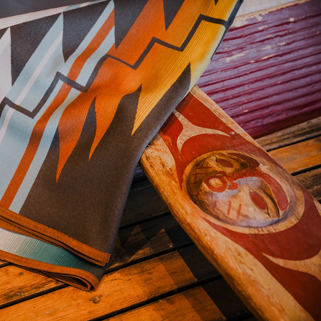 A blanket draped across a traditionally carved canoe